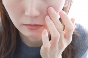 頬に手をあてスキンケアに悩む女性