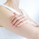 右腕を触る白い服を着た女性
