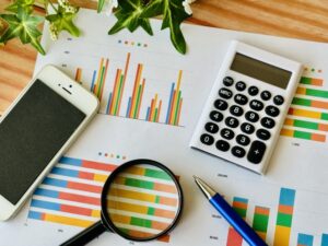 グラフや、スマホ、電卓、虫眼鏡が置いてある様子