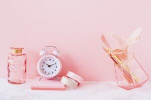 ピンク色の背景に時計が置いてある様子