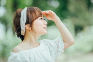 太陽の日差しを手で遮る女性