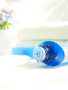 青色のボトルから化粧品がしたたる様子